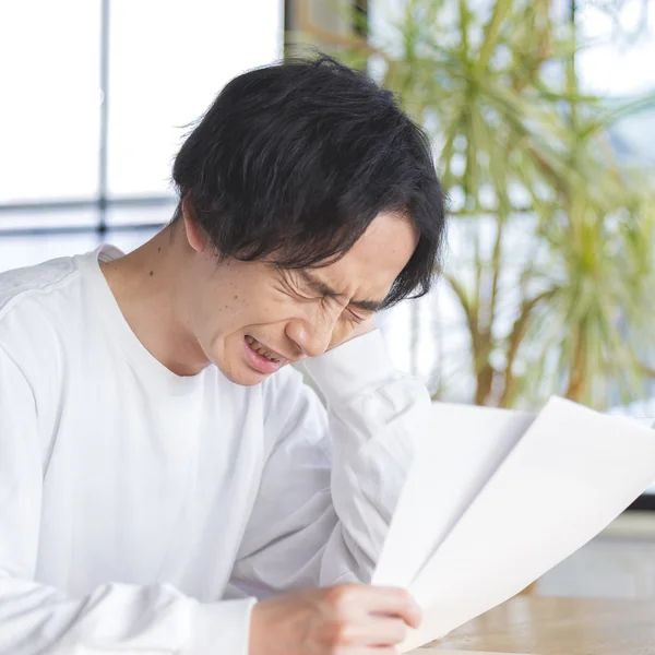 届いた書類を見て頭を抱える男性